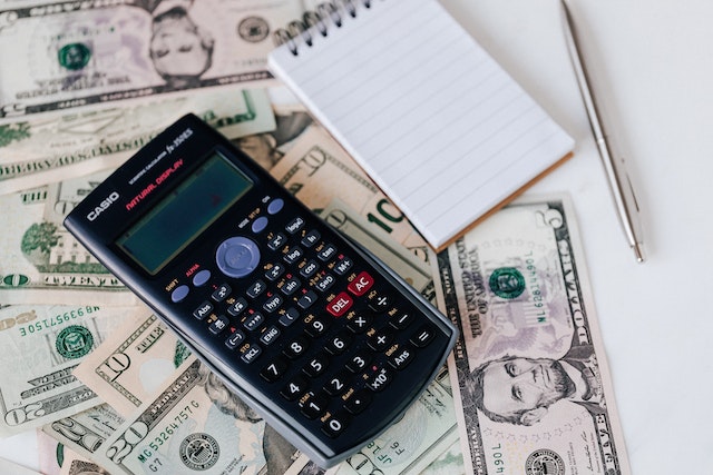 calculator and notepad on top of a spread out American cash